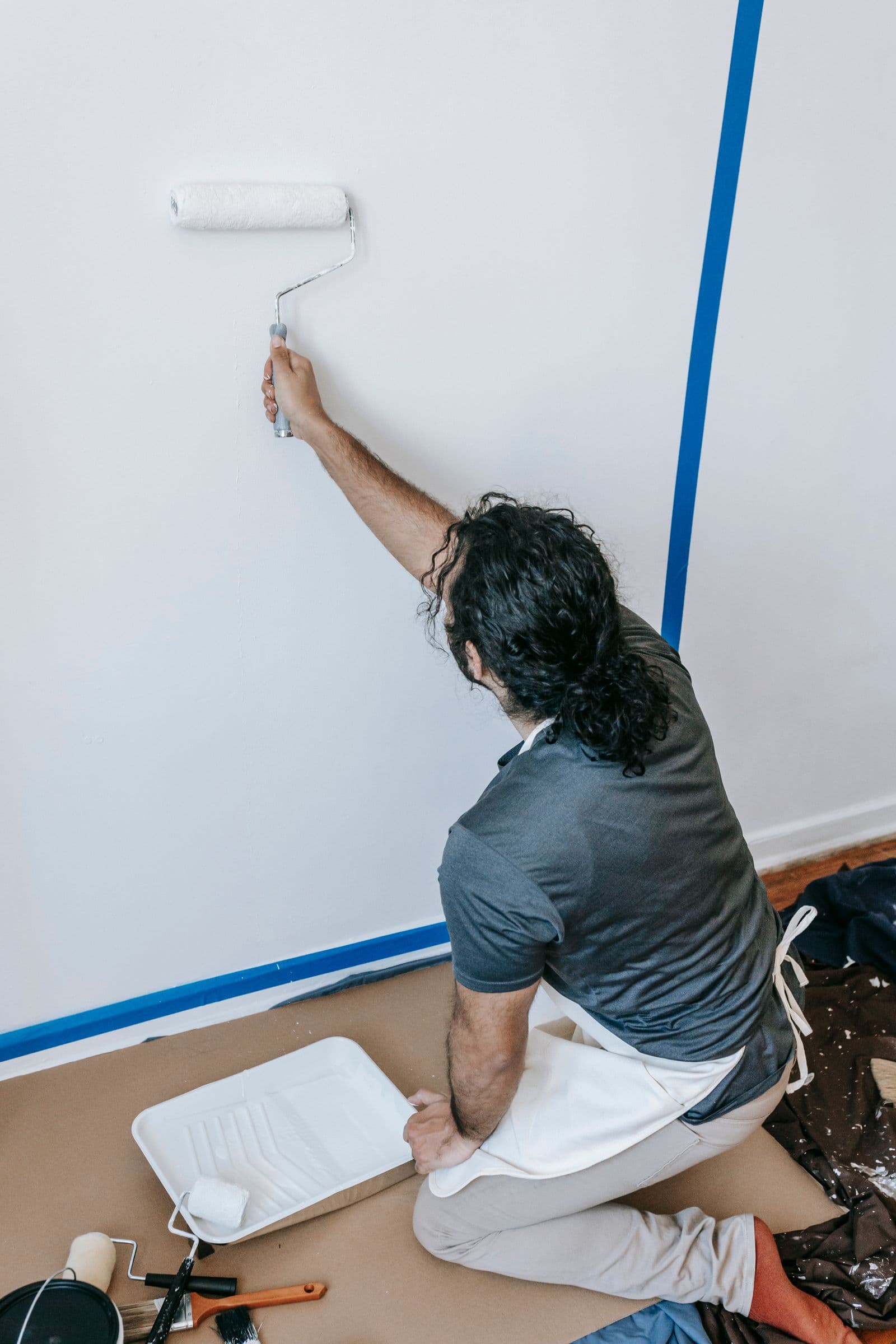 A professional painter applying a fresh coat of paint to an interior wall with a roller